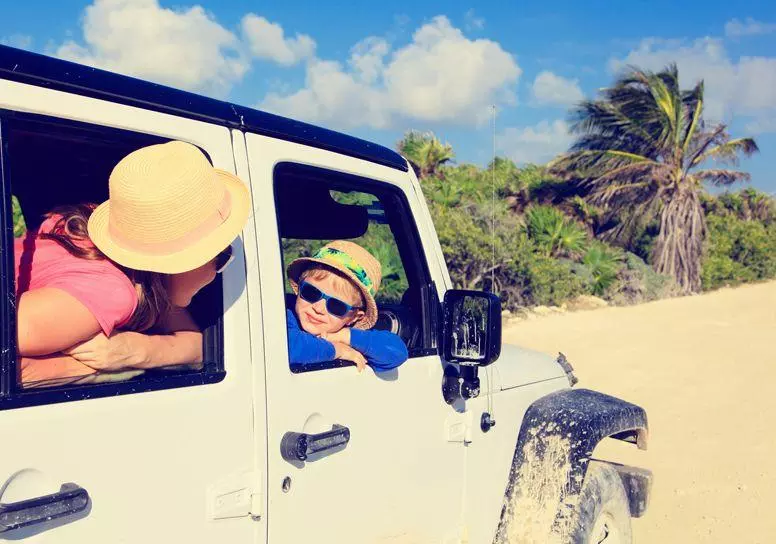 Family driving a jeep on the beach