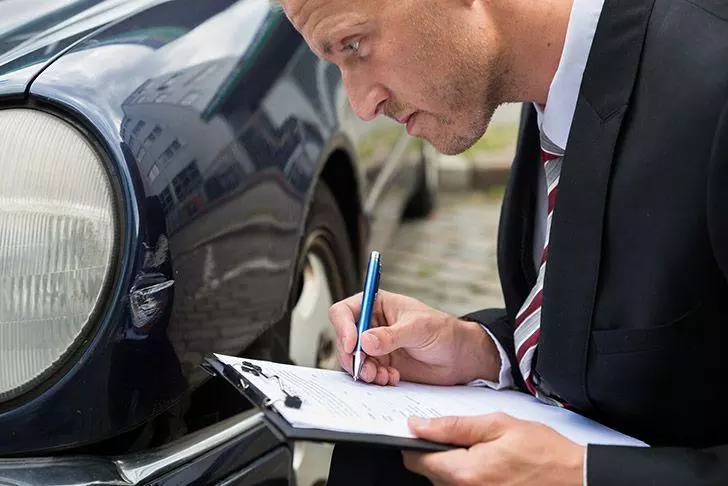 Person inspecting car for minor damage